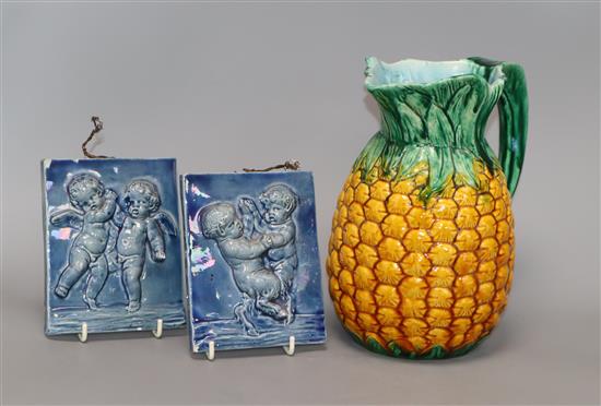 A Minton Majolica pineapple jug and two putti blue-glazed tiles tallest 12.5cm